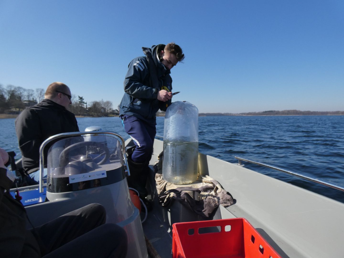 Środek jeziora Ińsko, student rozcina pierwszy worek z narybkiem i wpuszcza małe rybki do toni wodnej.